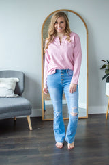 Model standing wearing pink long sleeve shirt and jeans.
